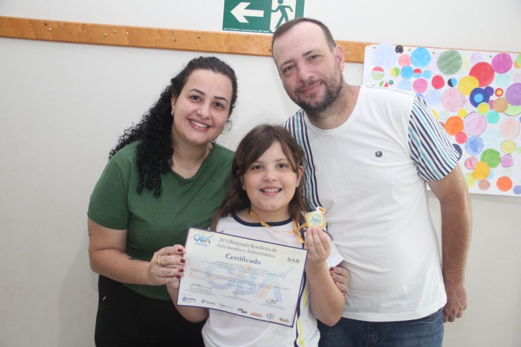 Flávia Vitória Basei com os pais orgulhosos da filha.